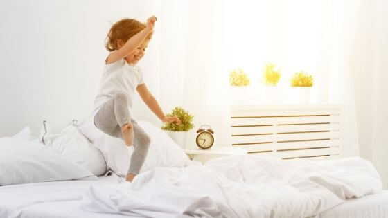 enfant qui s'amuse sur un lit